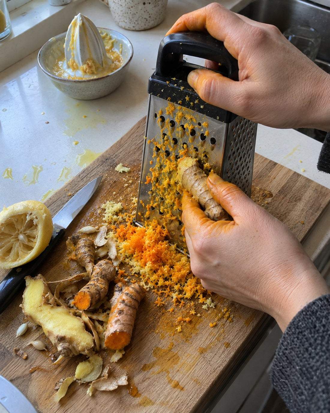 Grating ginger and turmeric at home with stained hands